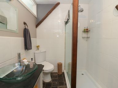 A bathroom with a glass sink toilet and a shower area at Cantref House Top Floor in Brecon