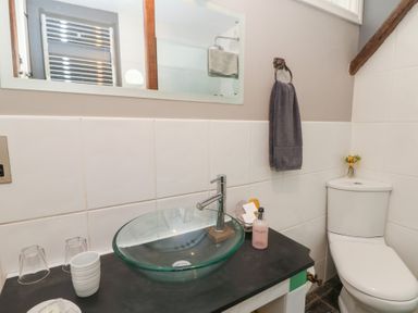 A bathroom with a glass sink on a black countertop and a white toilet in Cantref House Top Floor in Brecon