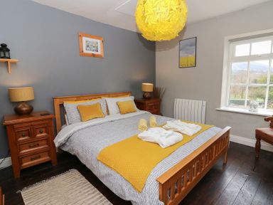 A bedroom with a wooden bed and yellow accents at Cantref House Top Floor in Brecon