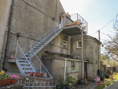 An outdoor metal staircase leading to a small balcony with chairs and potted plants at Cantref House Top Floor in Brecon