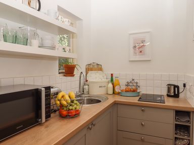A kitchen countertop with a microwave fruit basket sink and kettle at The Dairy at Wyke Farm Wyke near Lyme Regis