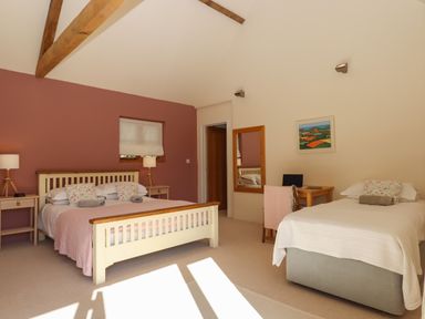 A bedroom with a double bed and a single bed a desk with a chair and a mirror on the wall at The Dairy at Wyke Farm Wyke near Lyme Regis