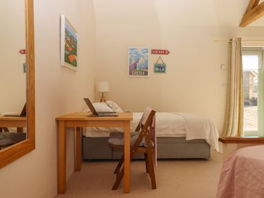 A bedroom with a single bed a wooden desk and chair a laptop on the desk and wall art at The Dairy at Wyke Farm in Wyke near Lyme Regis