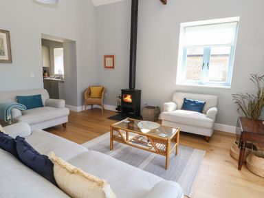 A living room with sofas a wicker chair coffee table and wood burning stove at Stapleford Farm in Hooke near Beaminster