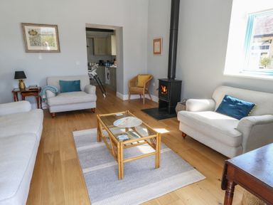 A living room with sofas a glass coffee table a wood-burning stove and a wicker chair at Stapleford Farm in Hooke near Beaminster