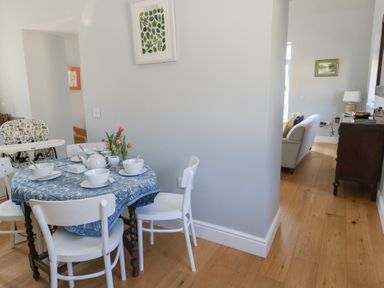 A dining area with a round table set for four and a high chair on wooden flooring at Stapleford Farm Hooke near Beaminster