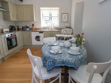 A kitchen with a round table set with bowls cups and a teapot and white chairs at Stapleford Farm in Hooke near Beaminster