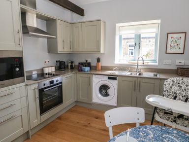 A kitchen with built in oven washing machine and sink next to a window at Stapleford Farm in Hooke near Beaminster