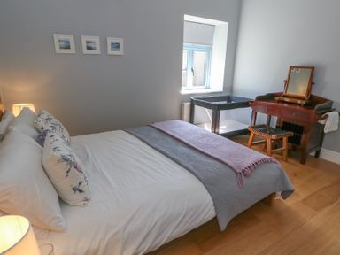 A bedroom with a bed a wooden dressing table and a baby crib by a window at Stapleford Farm in Hooke near Beaminster