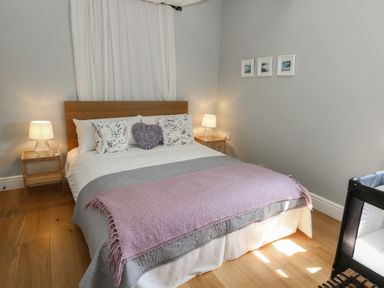 A bedroom with a double bed two bedside tables with lamps and framed pictures on the wall at Stapleford Farm in Hooke near Beaminster