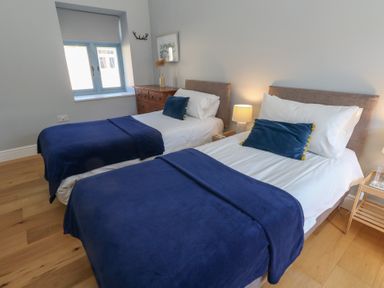A bedroom with two single beds blue blankets wooden chest of drawers and bedside lamp at Stapleford Farm in Hooke near Beaminster