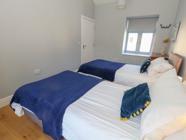 A bedroom with two single beds with blue blankets and pillows beside a window at Stapleford Farm in Hooke near Beaminster
