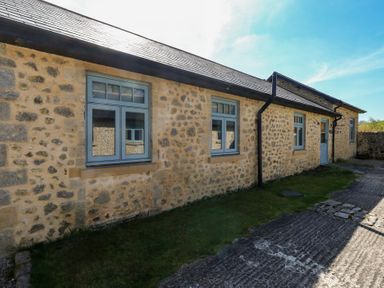 Exterior view of a stone building with three blue framed windows and a blue door at Stapleford Farm in Hooke near Beaminster