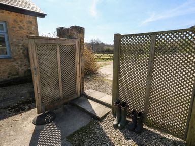A garden gate with wooden lattice panels and two pairs of rubber boots at Stapleford Farm in Hooke near Beaminster