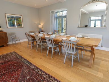 A dining room with a wooden table set for eight and wooden chairs at Stapleford Farm in Hooke near Beaminster