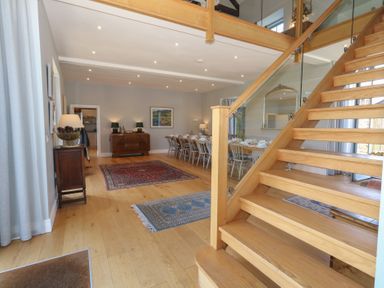 A dining room with wooden stairs rugs and tables set for a meal at Stapleford Farm in Hooke near Beaminster