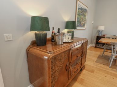 A wooden sideboard with two green lamps bottles and glasses in a dining area at Stapleford Farm Hooke near Beaminster