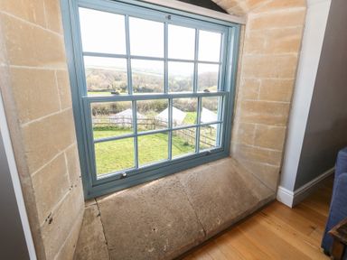 A blue framed window set in a stone wall overlooking a green garden at Stapleford Farm Hooke near Beaminster