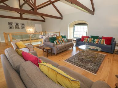 A sitting area with sofas armchairs a coffee table and a foosball table under exposed wooden beams at Stapleford Farm in Hooke near Beaminster