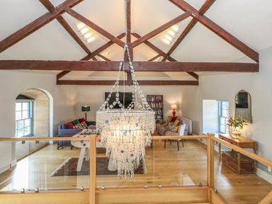 A living room with wooden beams a chandelier sofas a foosball table and a bookshelf at Stapleford Farm in Hooke near Beaminster