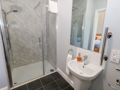 A bathroom with a shower enclosure and a sink with a mirror and towel at Stapleford Farm in Hooke near Beaminster