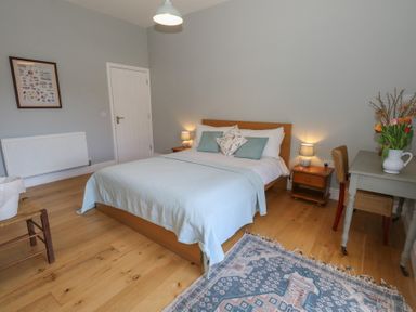 A bedroom with a bed bedside tables a desk with a chair and a rug on the floor at Stapleford Farm in Hooke near Beaminster