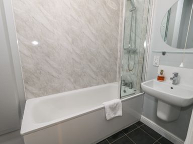 A bathroom with a bathtub shower combination and a sink with soap dispenser at Stapleford Farm in Hooke near Beaminster