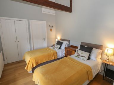 A bedroom with two single beds with yellow covers and wooden furniture at Stapleford Farm in Hooke near Beaminster