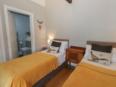 A bedroom with two single beds covered with yellow blankets and bird cushions at Stapleford Farm in Hooke near Beaminster