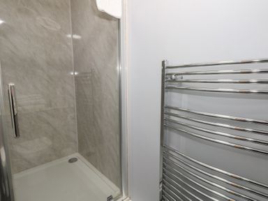 A bathroom with a glass shower enclosure and a chrome towel radiator at Stapleford Farm in Hooke near Beaminster