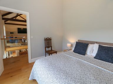 A bedroom with bed side table lamp wooden chair and wooden floor at Stapleford Farm Hooke near Beaminster