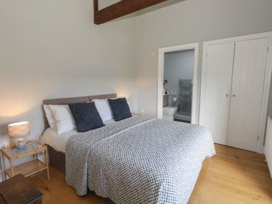A bedroom with a bed and bedside table next to an en suite bathroom at Stapleford Farm in Hooke near Beaminster