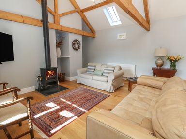 A living room with a wood burning stove two sofas wooden beams and a skylight at Stapleford Farm in Hooke near Beaminster