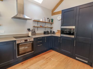 A kitchen with dark blue cabinets wooden shelves and wooden floor at Stapleford Farm in Hooke near Beaminster