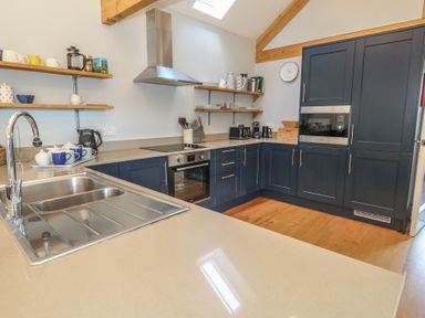 A kitchen with blue cabinets stainless steel sink and oven on wooden floor at Stapleford Farm in Hooke near Beaminster