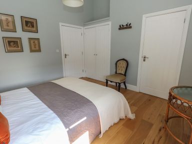 A bedroom with a bed a chair a round glass-top table and framed pictures on the wall at Stapleford Farm in Hooke near Beaminster