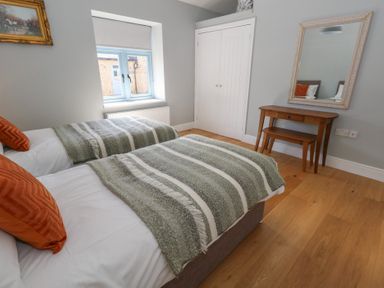A bedroom with two single beds with striped blankets a wooden dressing table with a mirror and a window at Stapleford Farm in Hooke near Beaminster