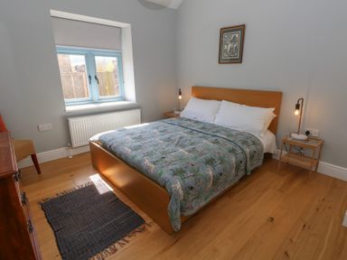 A bedroom with a bed and animal print bedspread a window a rug a chair and two bedside tables with lamps at Stapleford Farm in Hooke near Beaminster