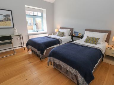 A bedroom with two single beds with blue and white bedding and a small table with books between Stapleford Farm Hooke near Beaminster