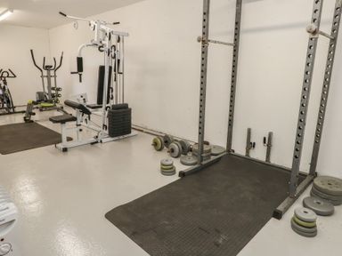 A gym room with various exercise equipment weights and machines at Stapleford Farm in Hooke near Beaminster