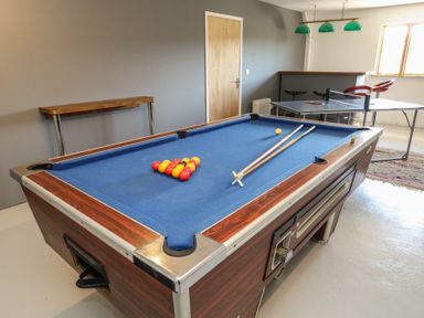 A game room with a blue pool table with balls and cues and a table tennis table with chairs at Stapleford Farm in Hooke near Beaminster
