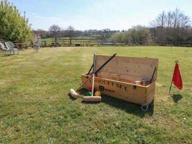 A croquet set on grass with mallets balls a wooden box and a red flag at Stapleford Farm in Hooke near Beaminster