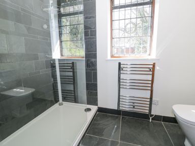 A bathroom with a shower area a window and a towel radiator at Bwthyn y Coediwr The Woodcutters Cottage in Tan Y Bwlch Maentwrog