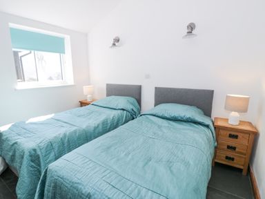 A bedroom with two single beds with blue bedding and wooden nightstands with lamps at Bwthyn y Coediwr (The Woodcutters Cottage) in Tan Y Bwlch Maentwrog