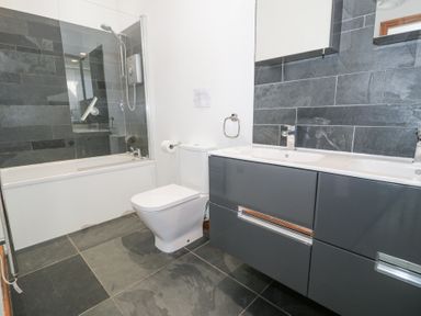 A bathroom with a bathtub shower toilet and double sink vanity at Bwthyn y Coediwr in Tan Y Bwlch Maentwrog