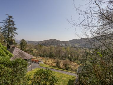 A house with outdoor seating and a gravel path overlooking trees and hills at Bwthyn y Coediwr The Woodcutters Cottage in Tan Y Bwlch Maentwrog