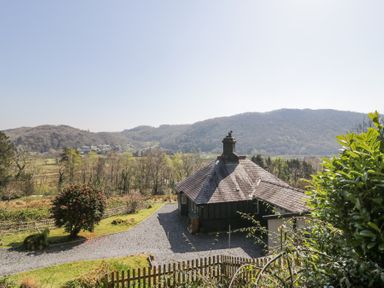 A cottage with a chimney surrounded by trees and hills at Bwthyn y Coediwr The Woodcutters Cottage in Tan Y Bwlch Maentwrog