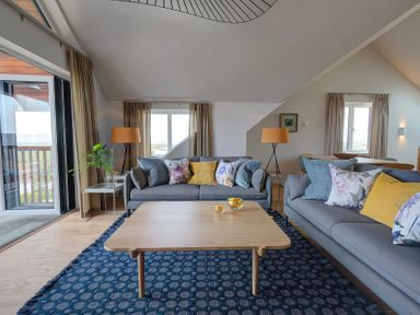 A living room with two sofas pillows a wooden coffee table a blue rug and lamps at Villa 4 Mullion