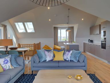 A living room with sofas and cushions next to a dining table and kitchen at Villa 6 in Mullion
