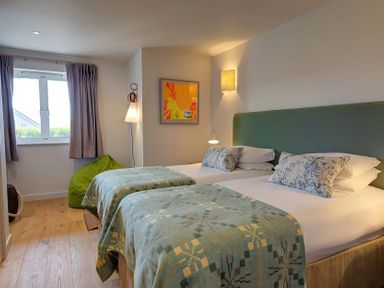 A bedroom with two single beds side by side a green bean bag near the window and a framed artwork on the wall at Villa 6 Mullion